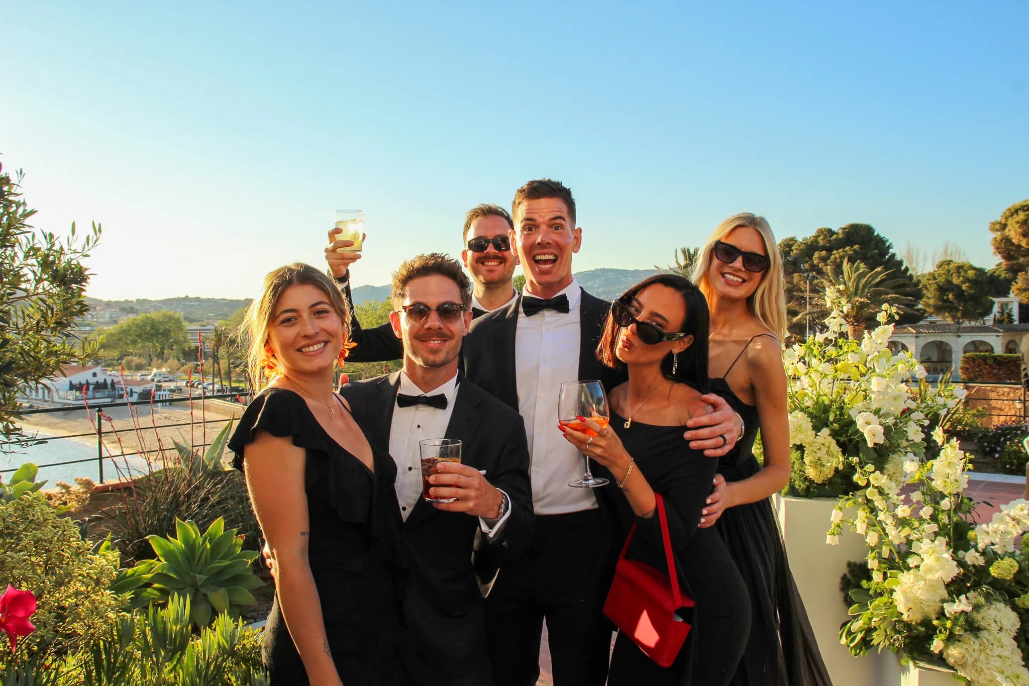 Invitados elegantes posando con el fotomatón vintage al atardecer