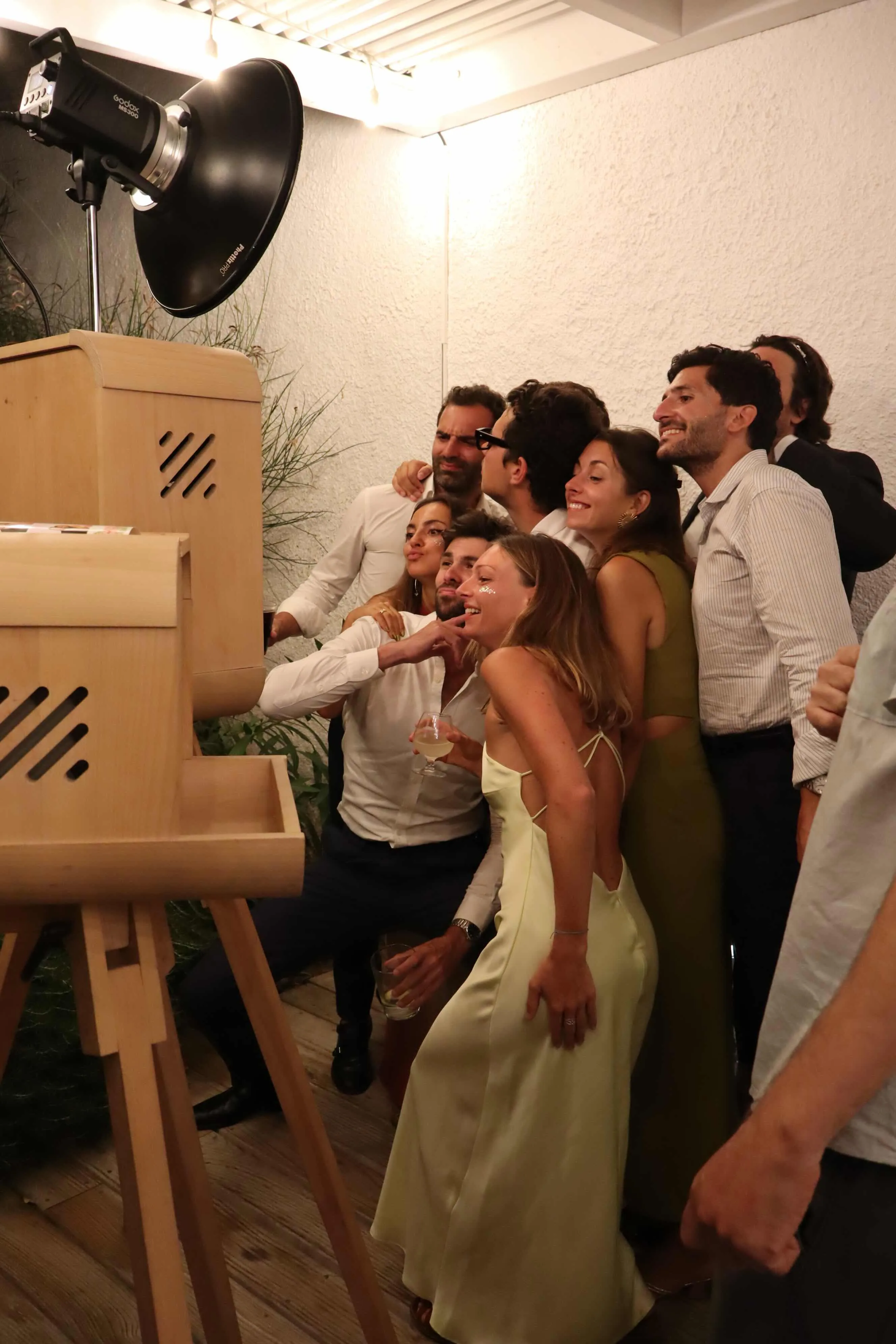 Grupo de invitados divirtiéndose con el fotomatón vintage en una boda nocturna