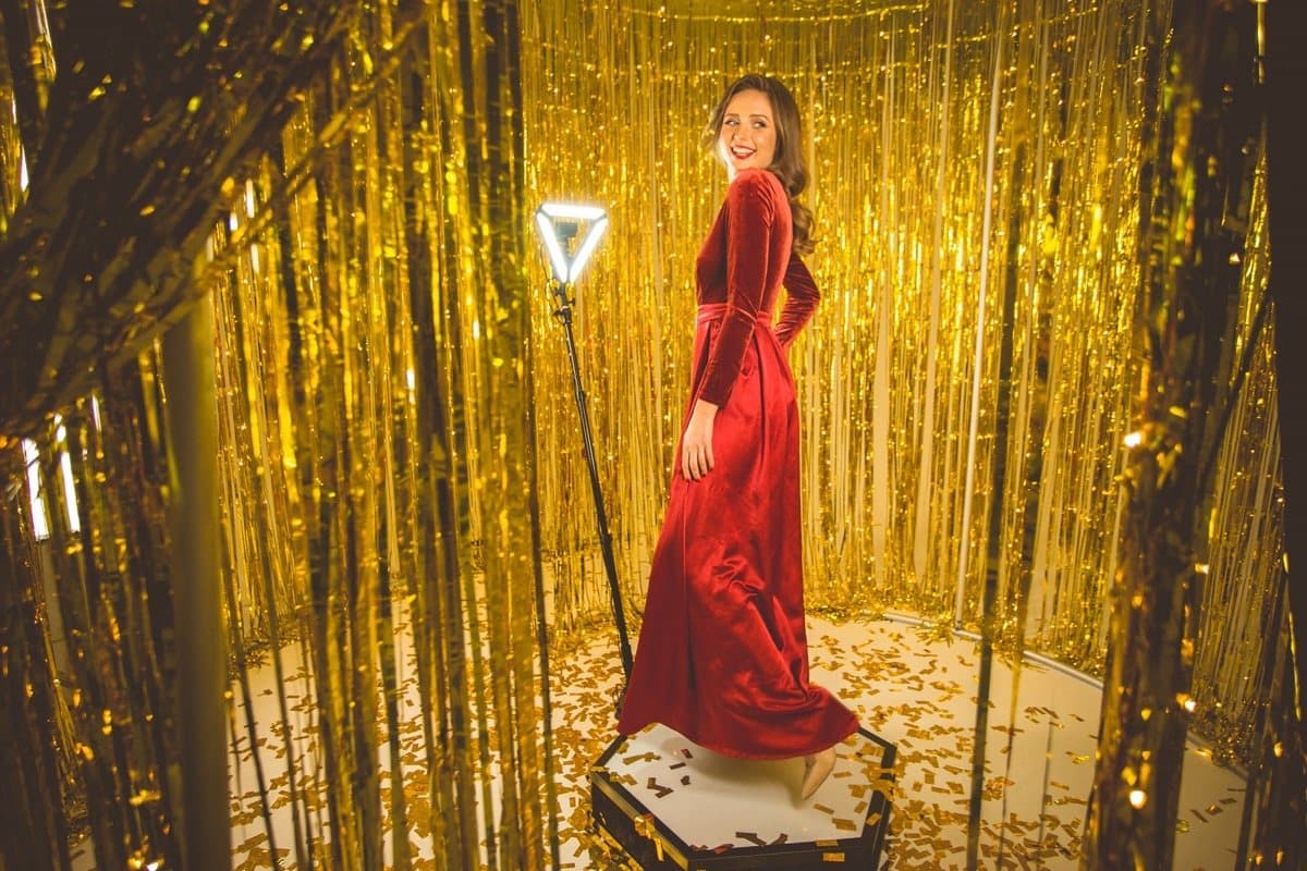 Guest recording a video on the 360° Spinner platform with gold backdrop