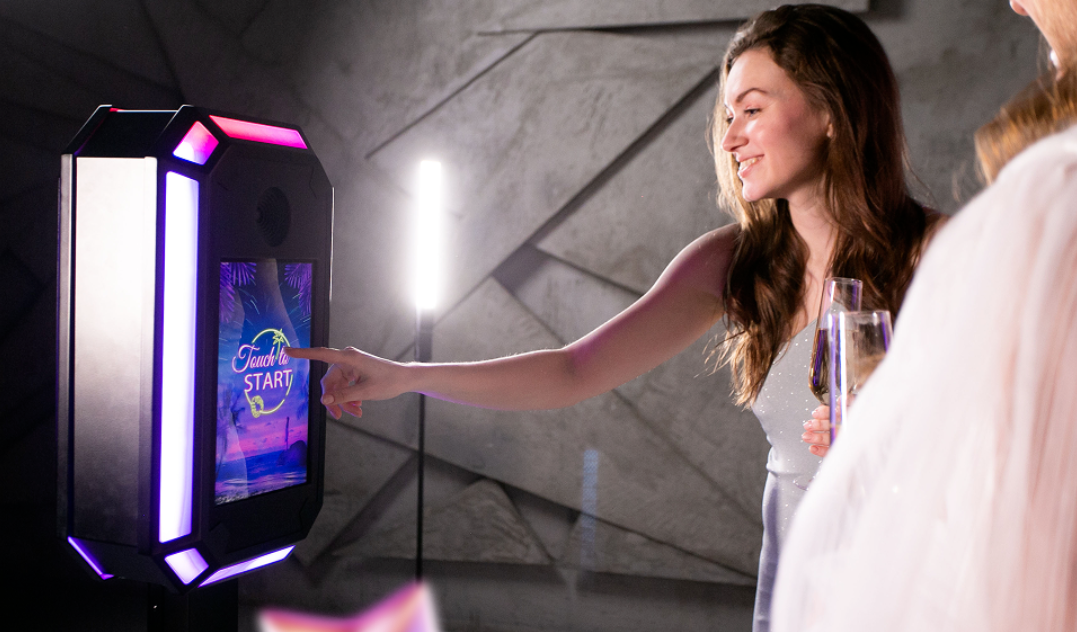 Un photobooth para eventos corporativos instalado con branding de la empresa, con un fondo profesional que realza la atmósfera de la reunión. Los invitados son invitados a capturar momentos divertidos y fotografías mientras participan en la fiesta temática, mostrando el logo de la empresa y creando recuerdos duraderos.